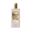 Frosted light pink rectangular perfume bottle with a gold-toned cap and an illustrated label depicting a golden cityscape wit