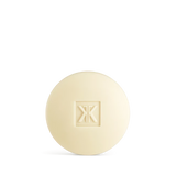 A round, cream-colored bar of Maison Francis Kurkdjian 724 scented soap featuring the brand's monogram logo embossed in the center.