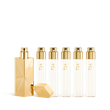 A luxury fragrance travel set featuring a sculptural gold travel spray case alongside five clear 11ml glass perfume refills labeled "724" with gold spray nozzles.