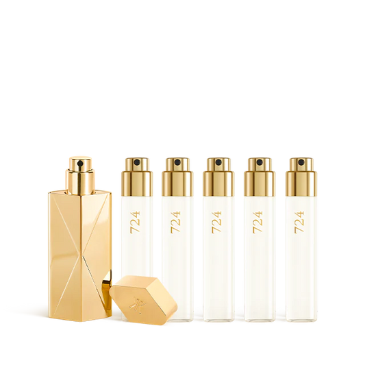 A luxury fragrance travel set featuring a sculptural gold travel spray case alongside five clear 11ml glass perfume refills labeled "724" with gold spray nozzles.