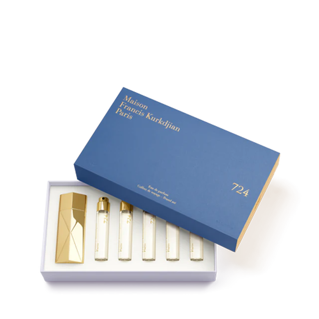 The Maison Francis Kurkdjian 724 travel set displayed in an open blue presentation box with gold lettering, neatly housing the gold Globe Trotter case and five 11ml refills.