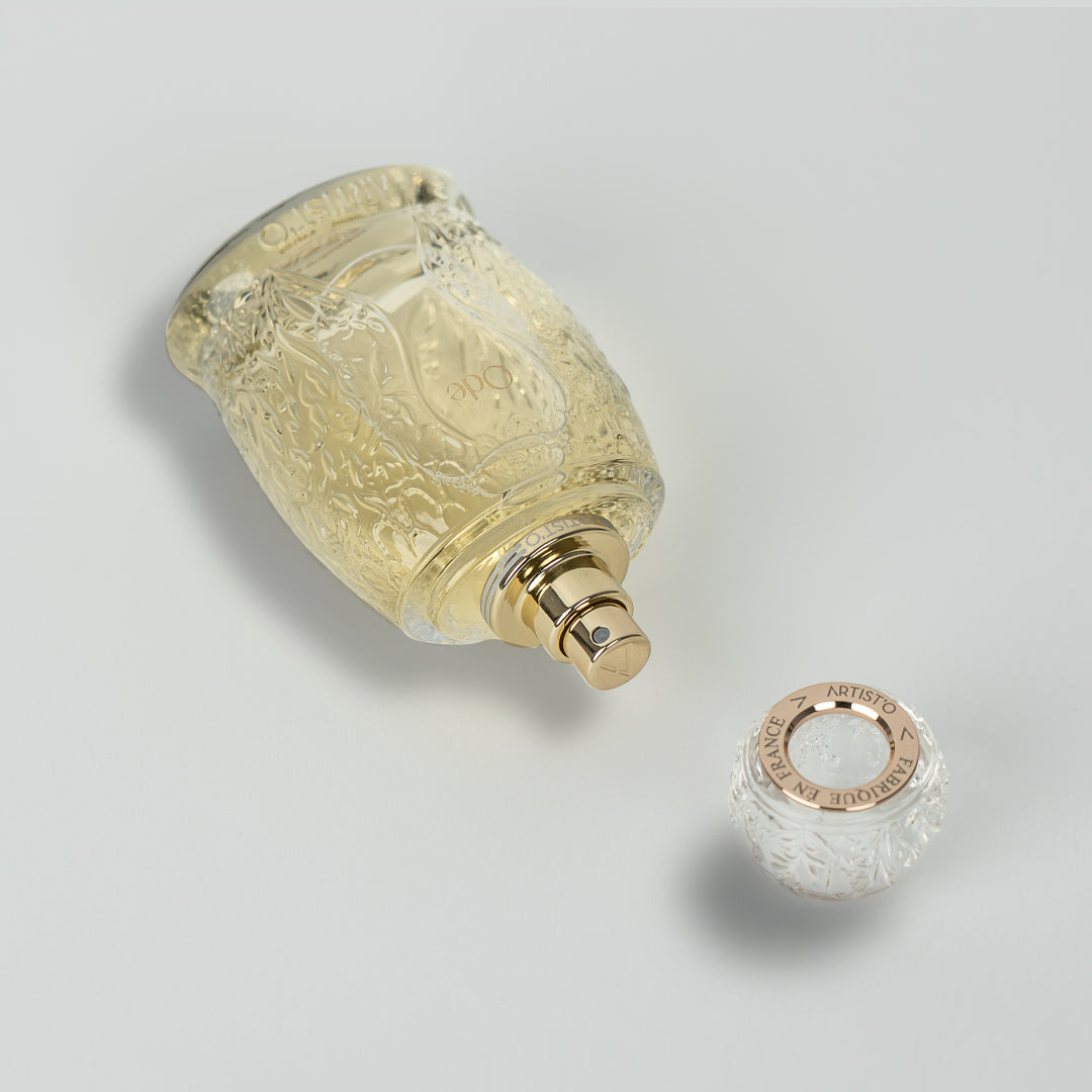 Artist’O Ode Eau de Parfum in an ornate clear glass bottle with a soft ivory fragrance, displayed with pastel pink luxury packaging – Find Online Today