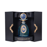 Teal glass perfume bottle with gold-toned and blue mosaic patterns, topped with a matching cap, presented in an open black bo