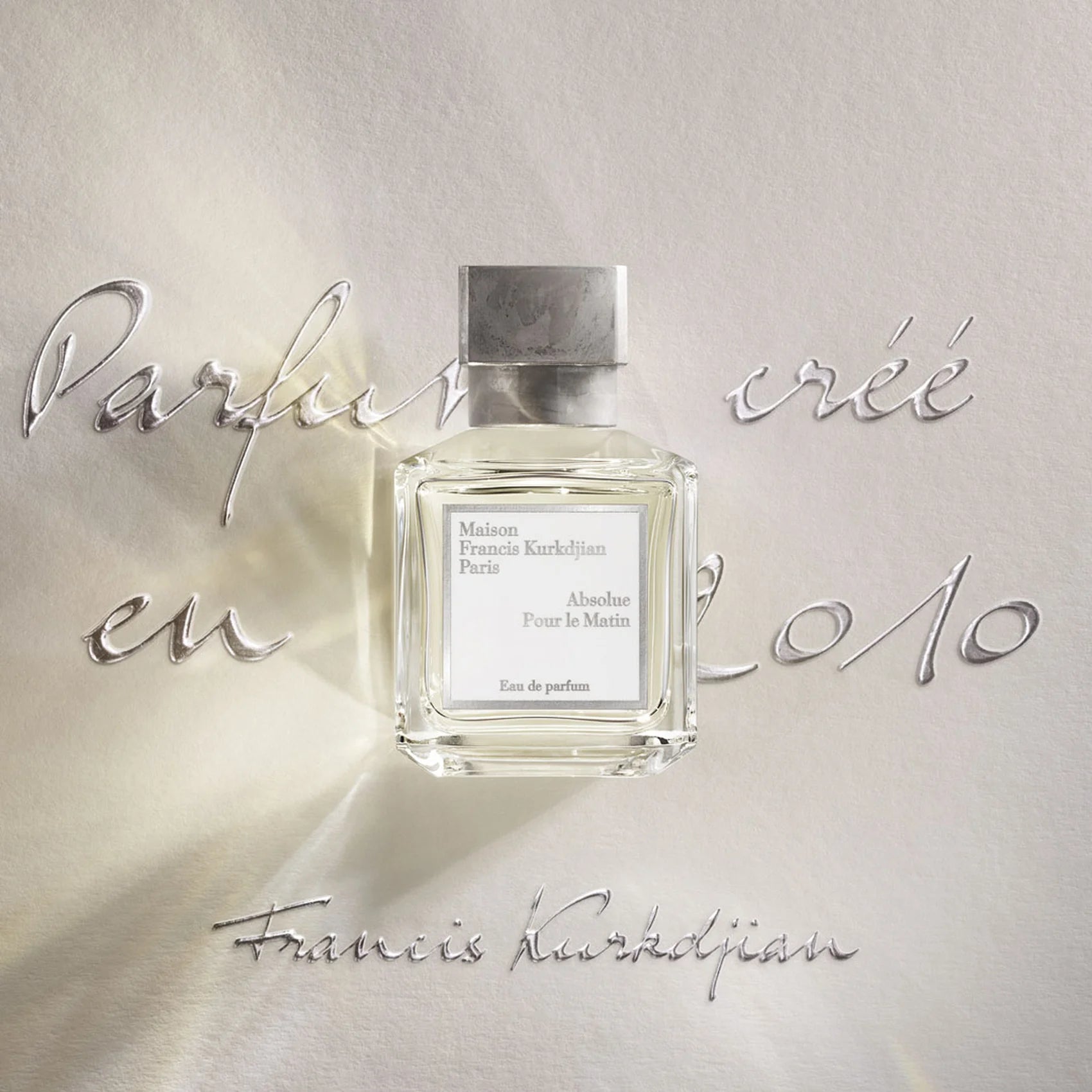 Rectangular clear glass perfume bottle with a light yellow liquid, a gray textured cap, and a white label.
