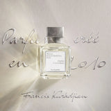 Clear rectangular perfume bottle with light yellow liquid, a white label, and a textured silver-toned cap.