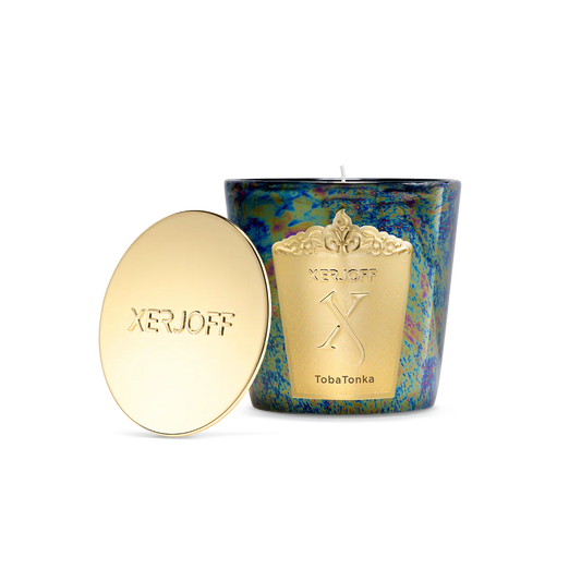A luxury TobaTonka scented candle and gold lid displayed inside a navy blue presentation box featuring a gold textured border and black velvet lining.