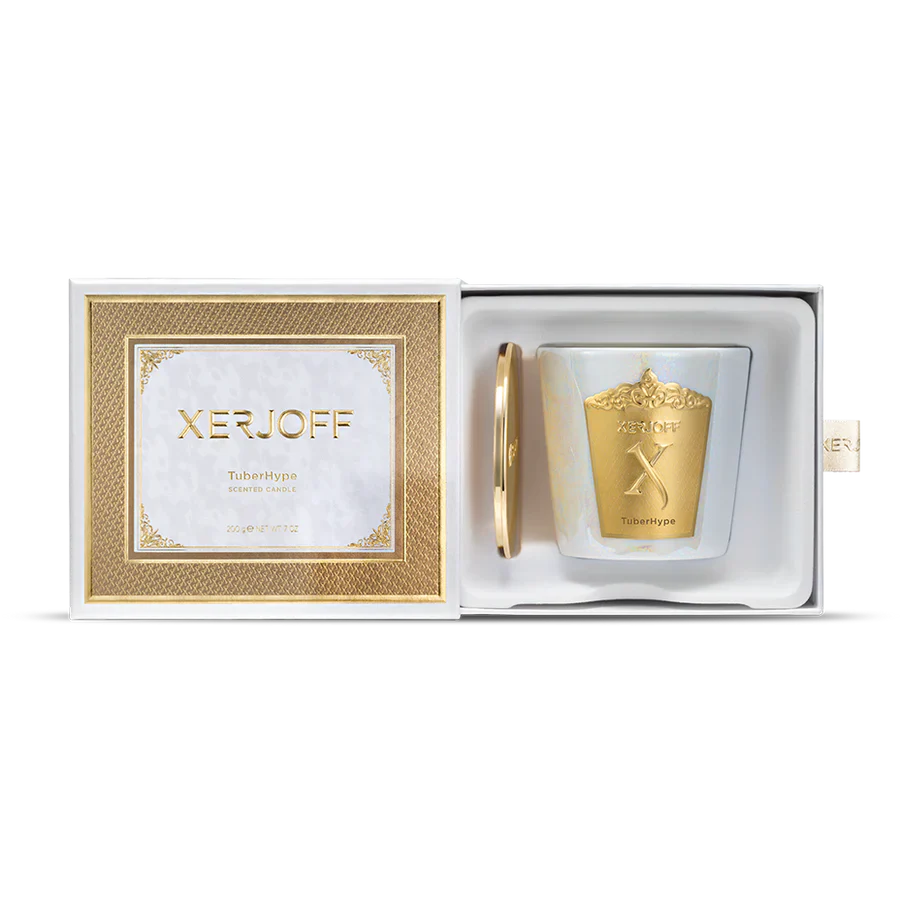 An iridescent white glass candle holder with a large decorative gold crest, shown next to a gold lid embossed with the Xerjoff brand name.