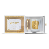An iridescent white glass candle holder with a large decorative gold crest, shown next to a gold lid embossed with the Xerjoff brand name.