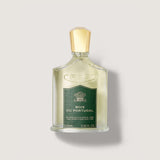 Rectangular clear glass fragrance bottle with light yellow liquid, a dark green label, and a gold-toned cap. 'CREED' is embos